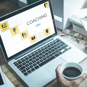 A laptop showing a coaching screen next to a cup of coffee