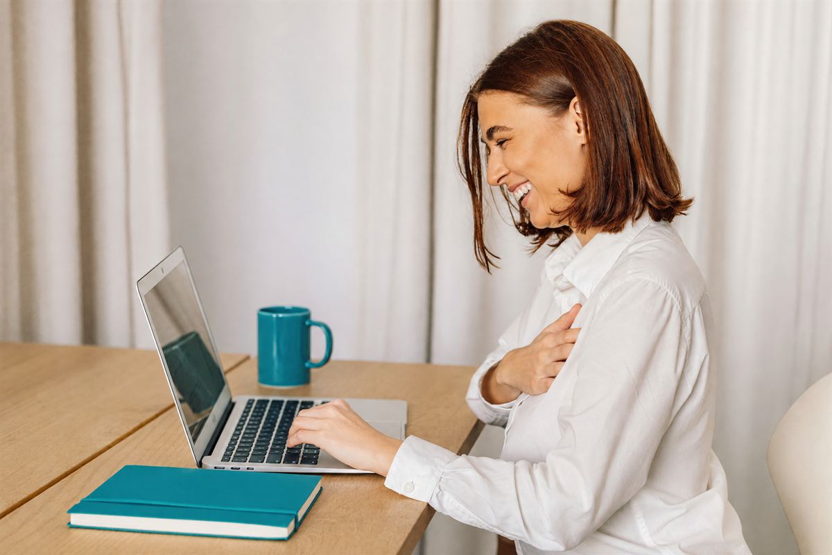 A practitioner smiling at her laptop as a long, hopeful enquiry arrives