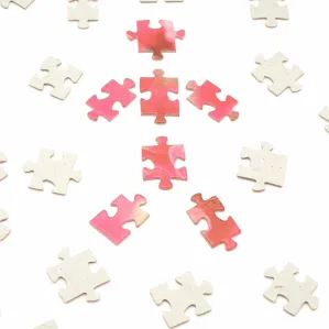 Scattered jigsaw pieces on a white background with a single coral piece at the centre