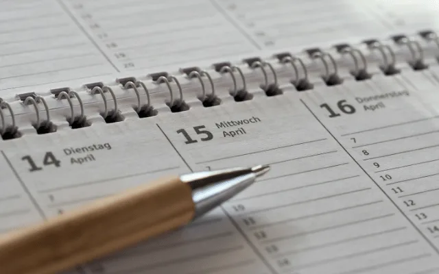 An open diary with a pen resting on the week's empty pages