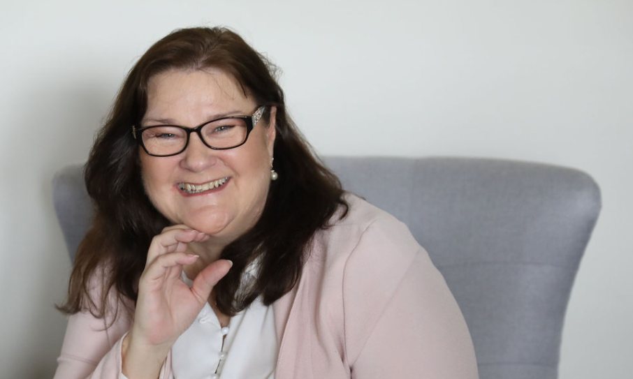 Carrie Wallis smiling, in a pink cardigan