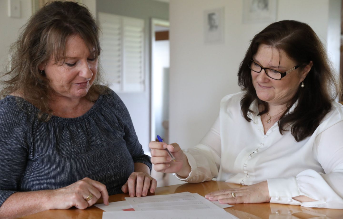 Carrie Wallis working through papers at a table with a client, pen in hand